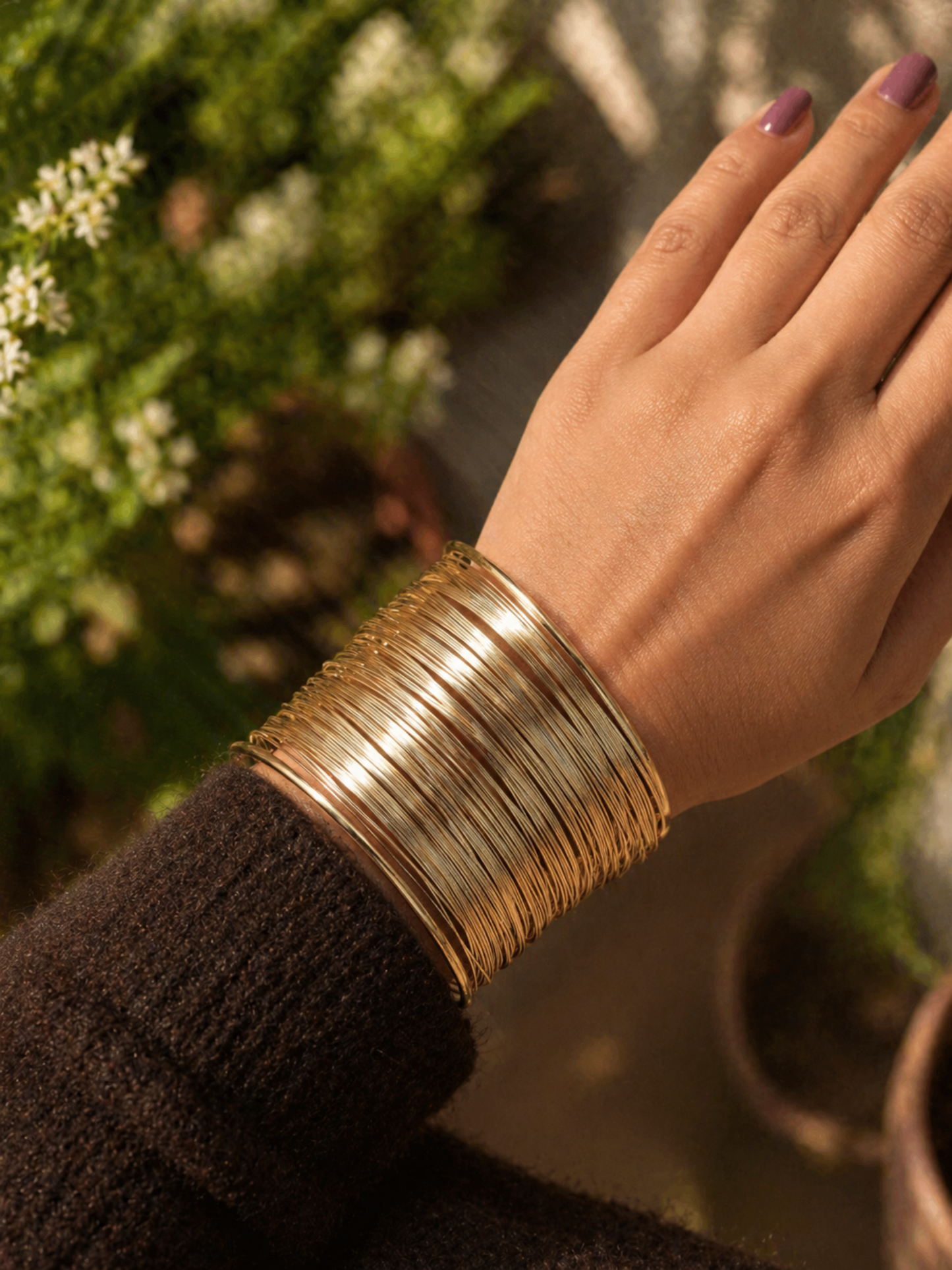gold cuff bracelet worn on wrist with textured knit sleeve