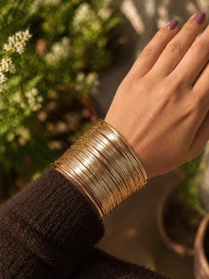 gold cuff bracelet worn on wrist with textured knit sleeve