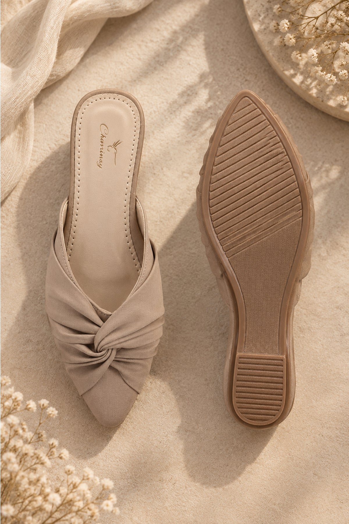 Beige backless mule shoes featuring a sculptural knot design