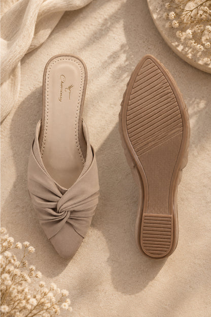 Beige backless mule shoes featuring a sculptural knot design