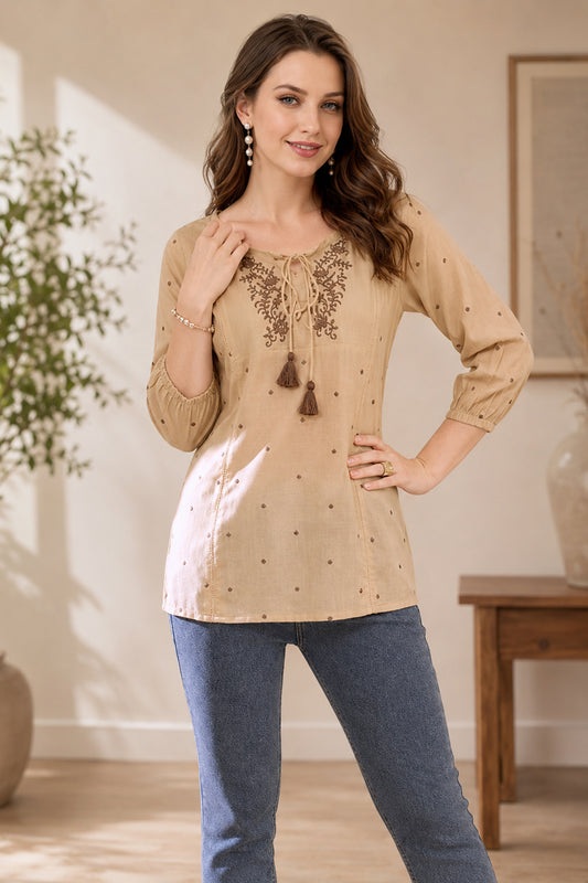 Woman wearing beige embroidered tunic with tassel neckline